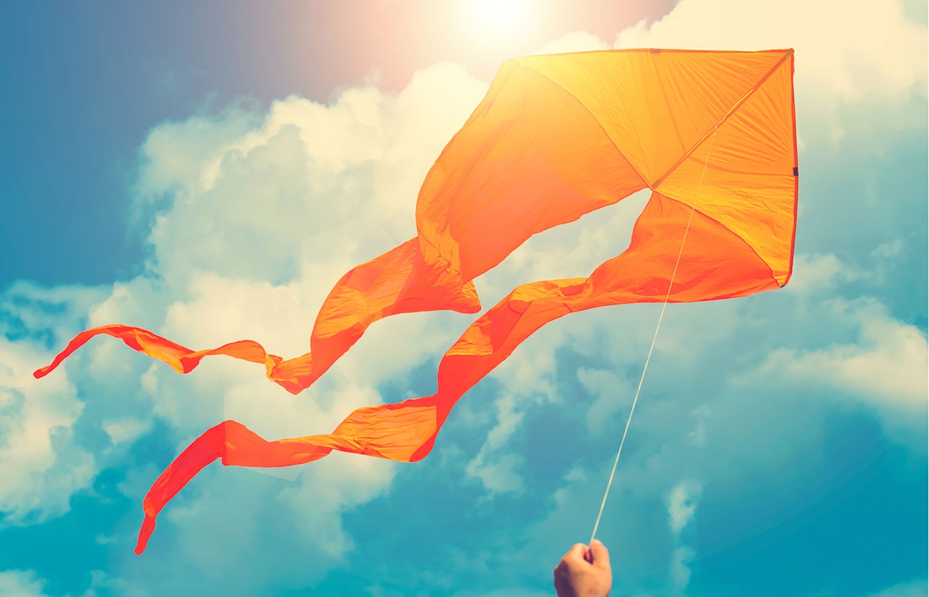 Flying orange kite on a sunny day