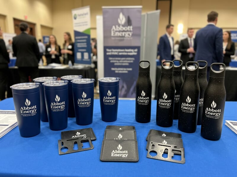 manufacturing hiring booth with insulated drinkware, tote bags, drawstring bags, and candidates