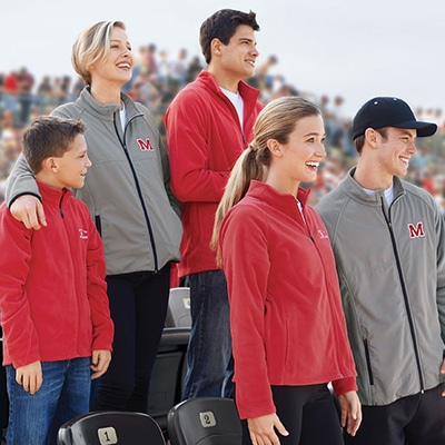 Sport fans standing in bleachers wearing fleece jackets customized with team logo