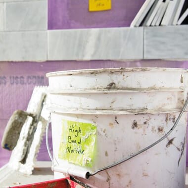 Dirty plastic bucket in a construction site labeled with a Post-it Extreme Sticky Note