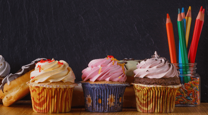 colored pencils, cupcakes, and donuts on teacher's desk