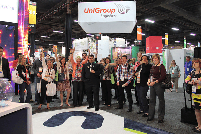 Crowd of people cheering at a trade show booth for the company UniGroup Logistics